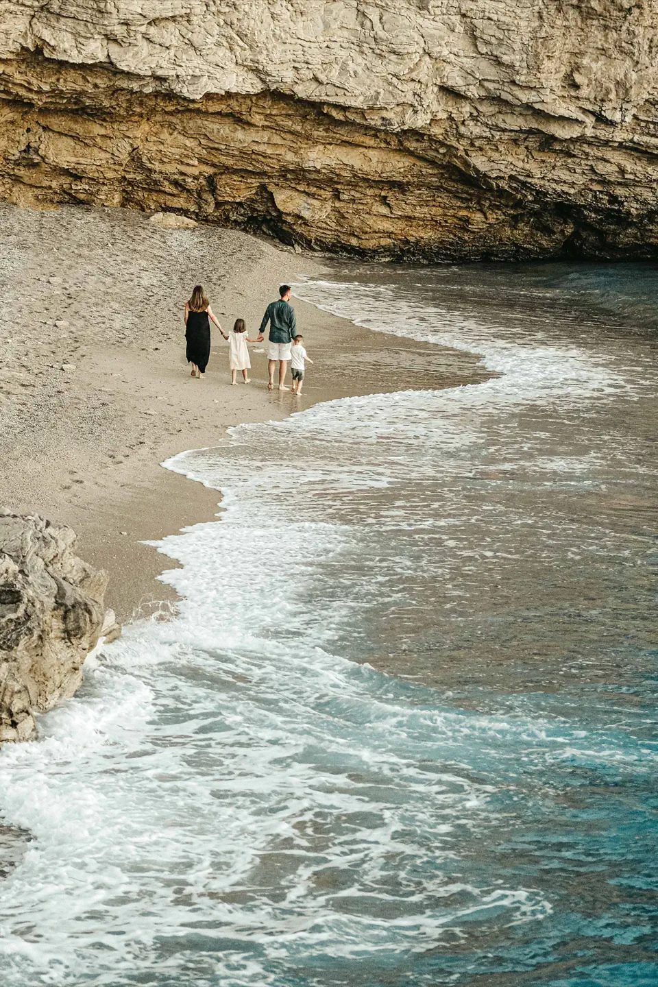 A family walking at the water’s edge on a quiet Sanur cove.